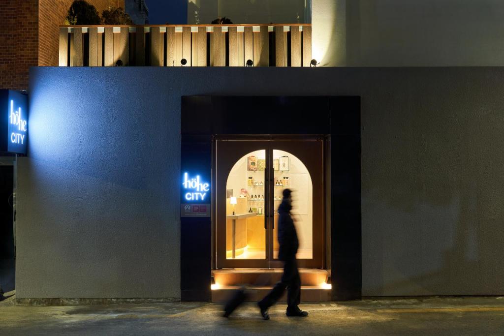 a man walks past a window of a blue city at Hohe City Dongdaemun in Seoul