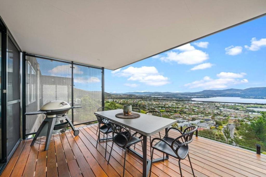 a room with a table and chairs on a deck with a view at Rosetta Vista - Architectural Haven with River Views in Berriedale