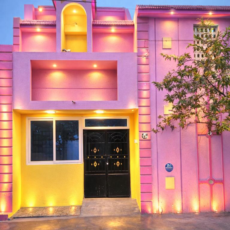 a pink and yellow building with a black door at CR Private Villa in Tiruvannāmalai