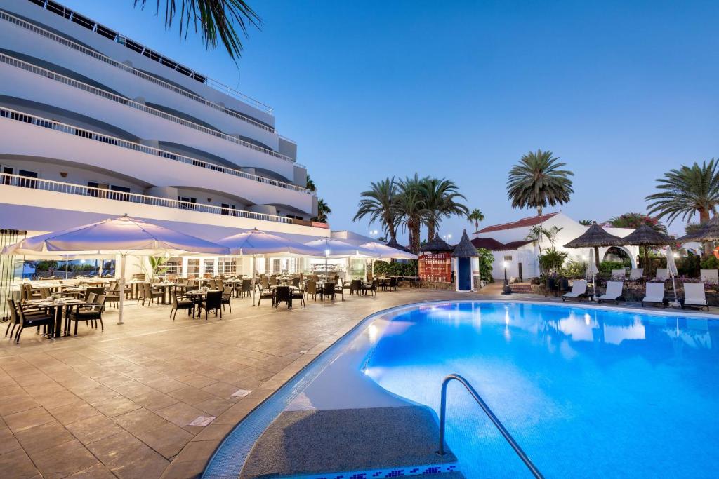 a swimming pool in front of a hotel with tables and umbrellas at SOL by Meliá Barbacan in Playa del Ingles