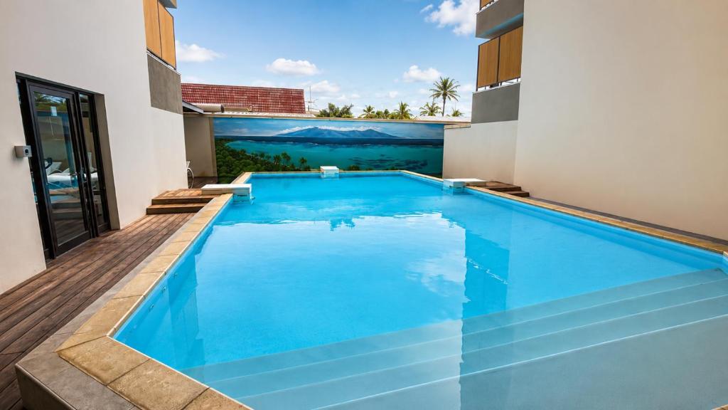 a swimming pool in the middle of a house at Blue Lagoon - Studio avec accès piscine in Papeete
