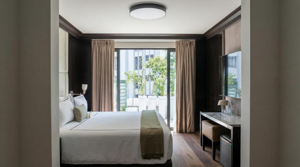 ein Schlafzimmer mit einem Bett und einem großen Fenster in der Unterkunft Hippodrome Hotel in Mexiko-Stadt