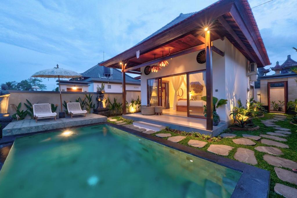 a villa with a swimming pool in front of a house at Mahayani Ubud Villa in Tegalalang