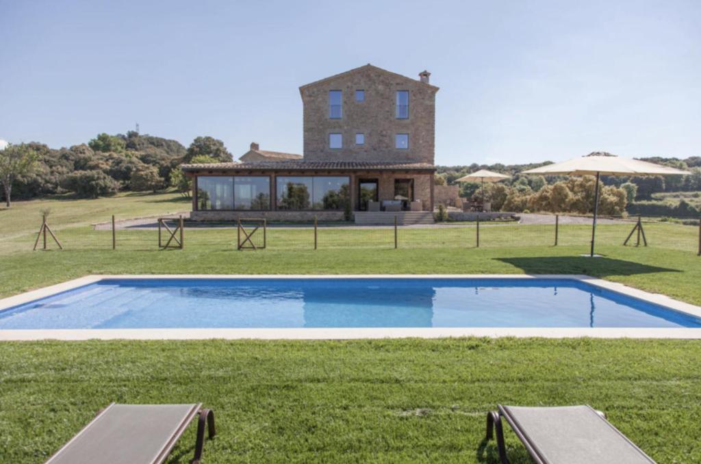 a villa with a swimming pool in front of a house at La Masoveria de Mateus in Sagás
