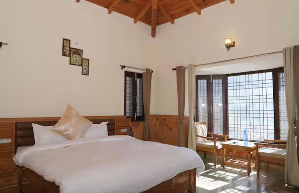 a bedroom with a white bed and a table and chairs at Voyager stone cottage in Bhīm Tāl
