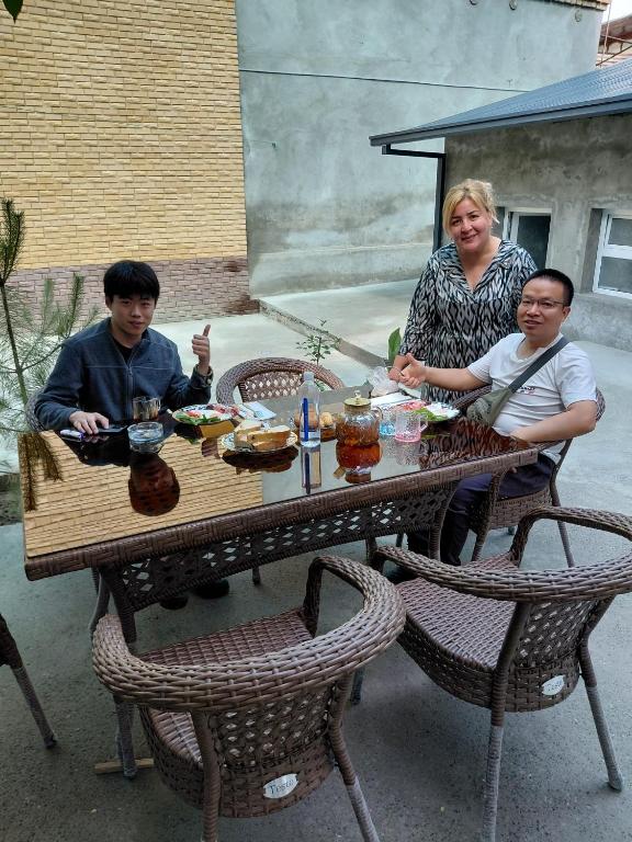 a woman and two people sitting at a table at Nazo&M Hotel in Shahrisabz