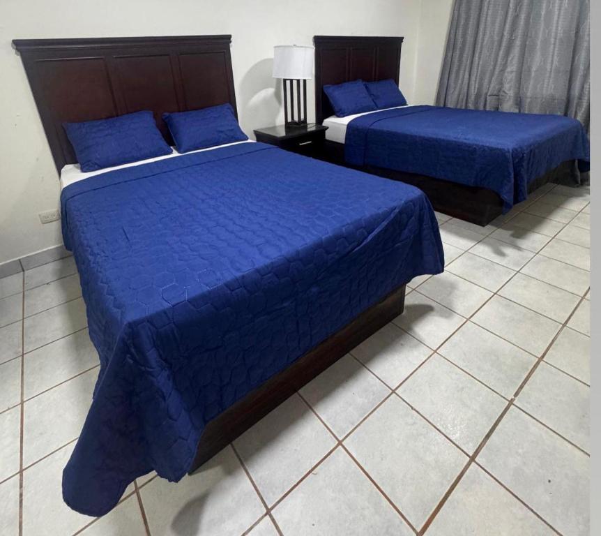 two beds in a room with blue sheets and blue pillows at Piñas Room in El Pino