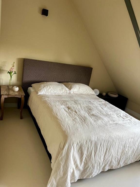 a bed with a white comforter and a side table at Private attic room with workspace & water view in Haarlem