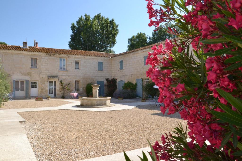 ein Gebäude mit einem Innenhof mit rosa Blumen in der Unterkunft Mas De Sylvereal in Sylvéréal