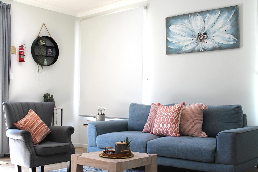 a living room with a blue couch and two chairs at Spacious Modern Acreage Getaway- close to Shopping mall in Browns Plains