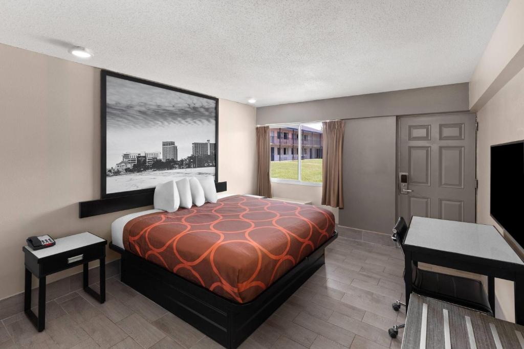 a hotel room with a bed and a desk and a window at Super 8 by Wyndham Biloxi at the Beach in Biloxi