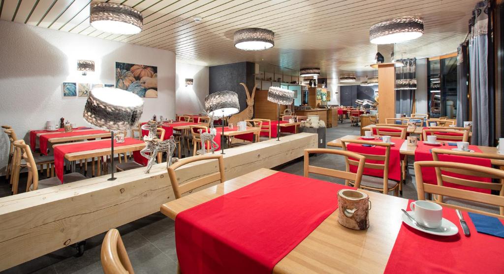 a restaurant with tables and chairs with red table cloth at Hotel du Lac in Crans-Montana