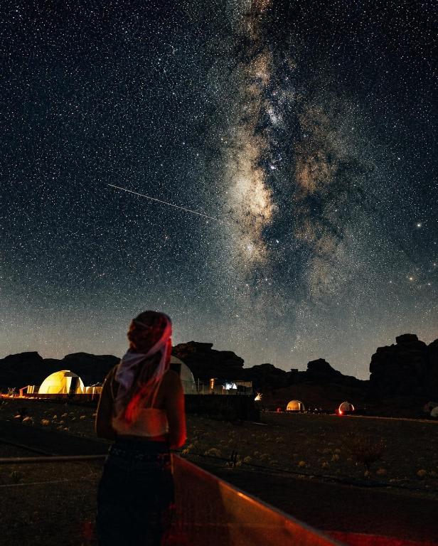 a woman is looking up at the night sky at Wadi Rum Bedouin Heart in Wadi Rum