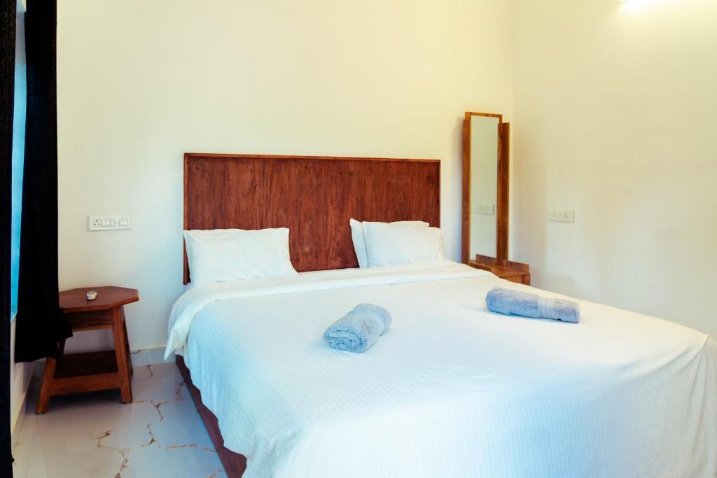 a bedroom with a large white bed with a wooden headboard at Kuma Surf House in Kappil
