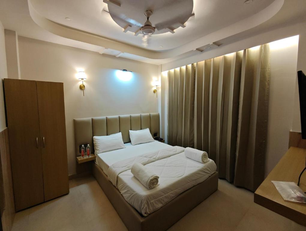 a bedroom with a bed with white sheets and a ceiling at Hotel hk haridwar By hk guest house in Haridwār