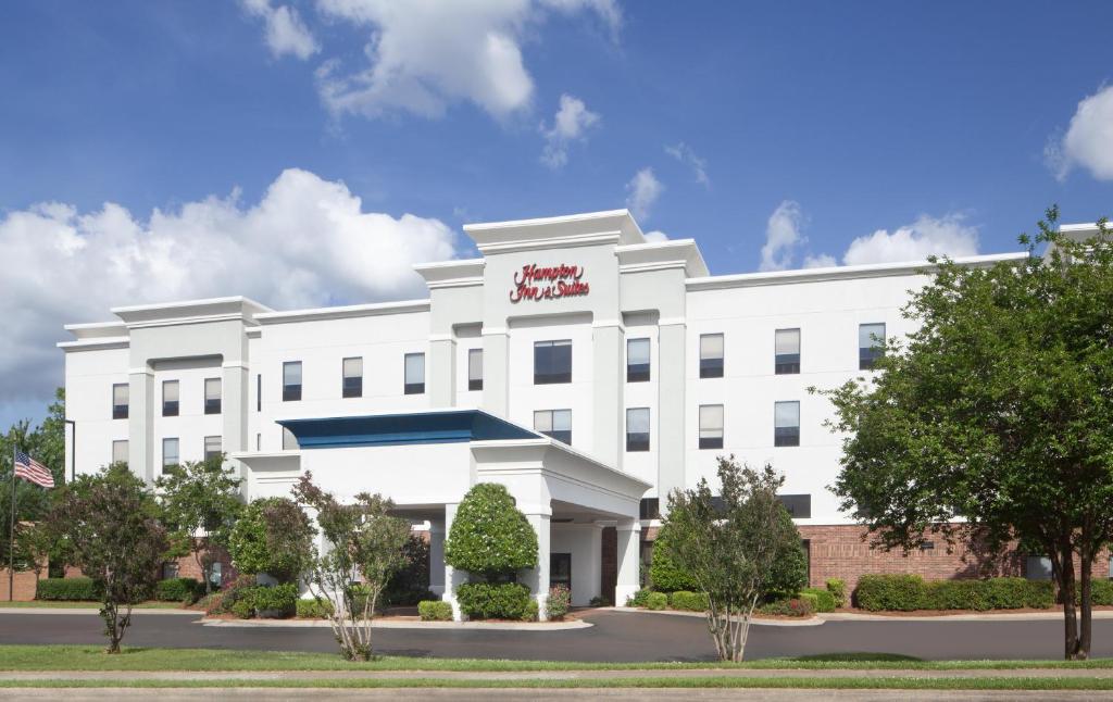 a white building with a red sign on it at Hampton Inn & Suites Natchez in Natchez