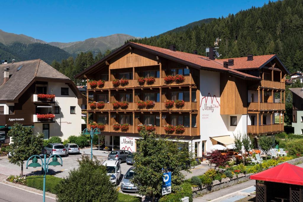 a hotel in the mountains with a parking lot at Hotel Moritz in Dobbiaco