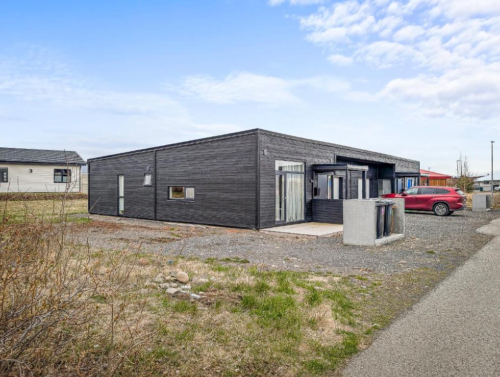a black house with a red car parked in front of it at Deluxe Family Apartment in Egilsstaðir in Egilsstaðir