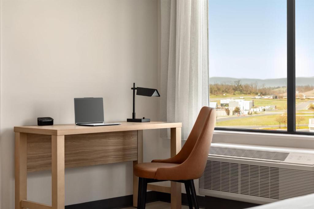a desk with a laptop and a chair next to a window at Hyatt Studios Harrisonburg in Harrisonburg