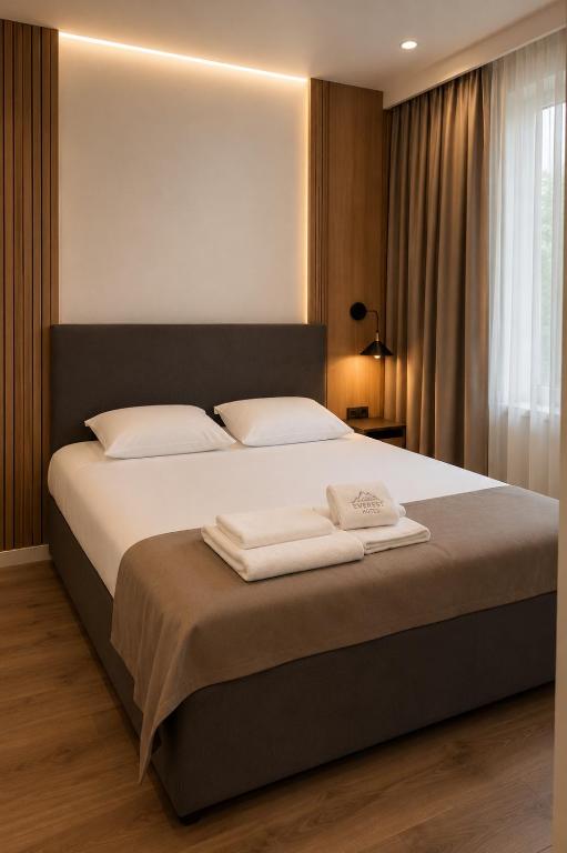 a bedroom with a large bed with two towels on it at Everest in Zyryanovsk