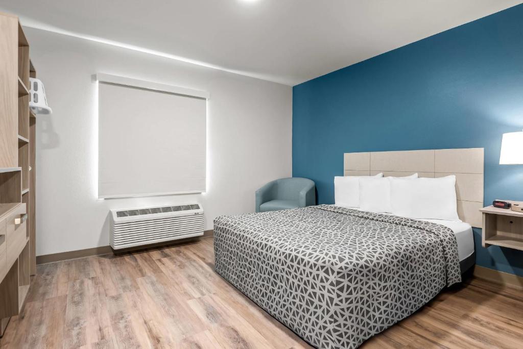 a bedroom with a bed and a blue wall at WoodSpring Suites Lancaster North in Lancaster