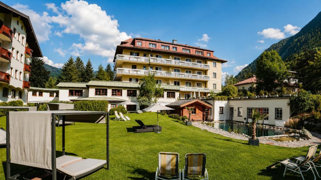 a hotel in the mountains with a yard with chairs at Hotel Rauscher - Das Naturteichparadies in Bad Hofgastein