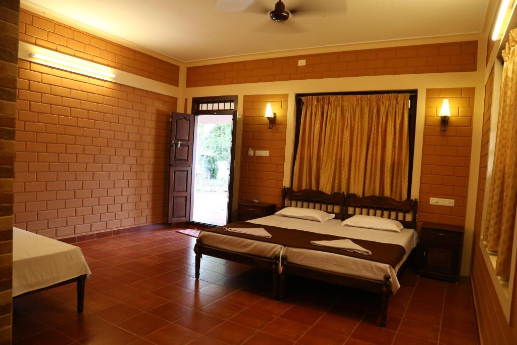 a bedroom with two beds and a window and a door at Dazzle Dew in Alleppey