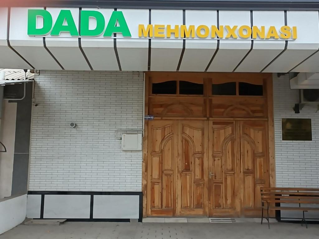 a building with a wooden door and a sign on it at Dada guest house in Bukhara