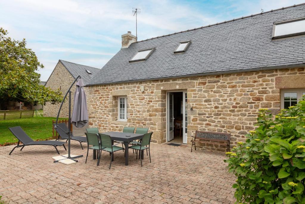 a patio with a table and chairs in front of a brick building at Gîte Ty Traon piscine partagée in Ergué-Gabéric