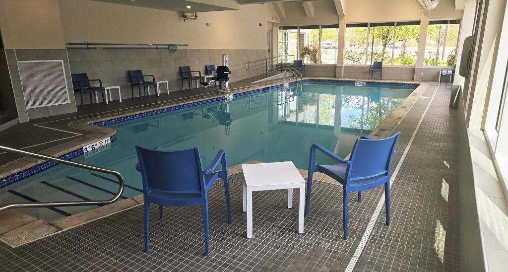 a swimming pool with blue chairs and a table in it at Comfort Inn Concord South End in Concord