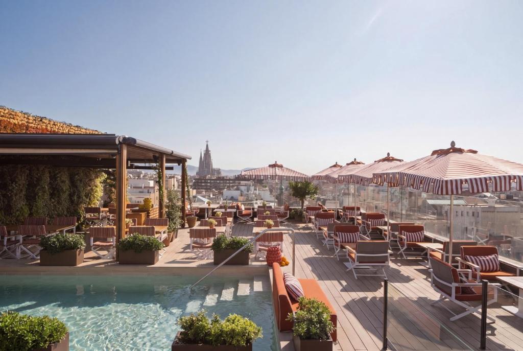 a swimming pool with chairs and umbrellas on a building at Majestic Hotel & Spa Barcelona GL in Barcelona