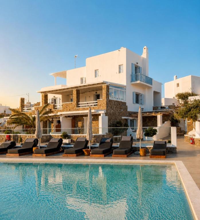 a villa with a swimming pool in front of a building at Crystal Suites in Mikonos