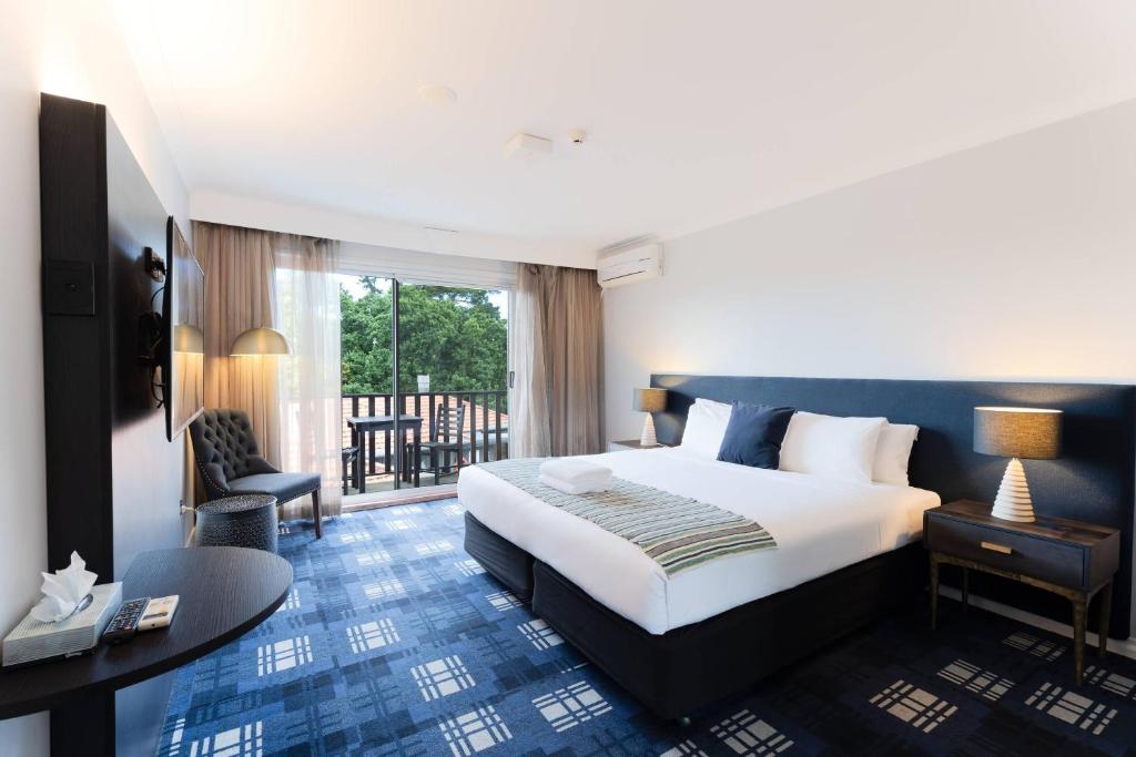 a hotel room with a large bed and a desk at Comfort Resort Leura Gardens in Leura