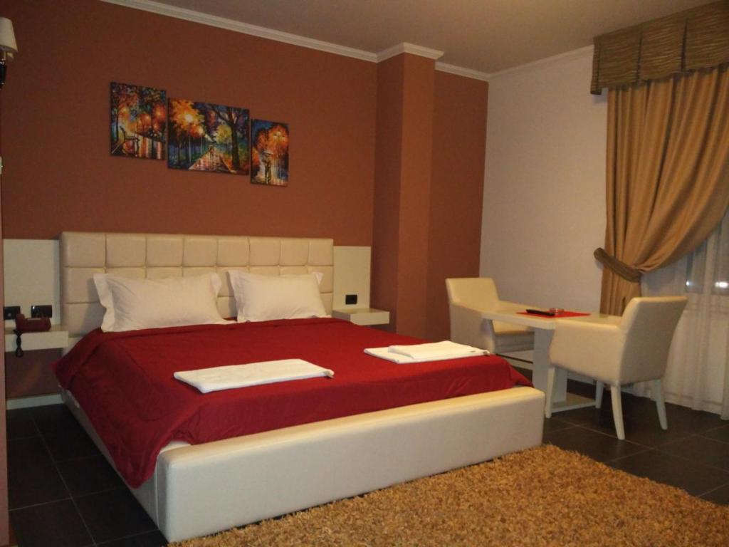 a bedroom with a bed and a table and chairs at Hotel Mustang in Tirana