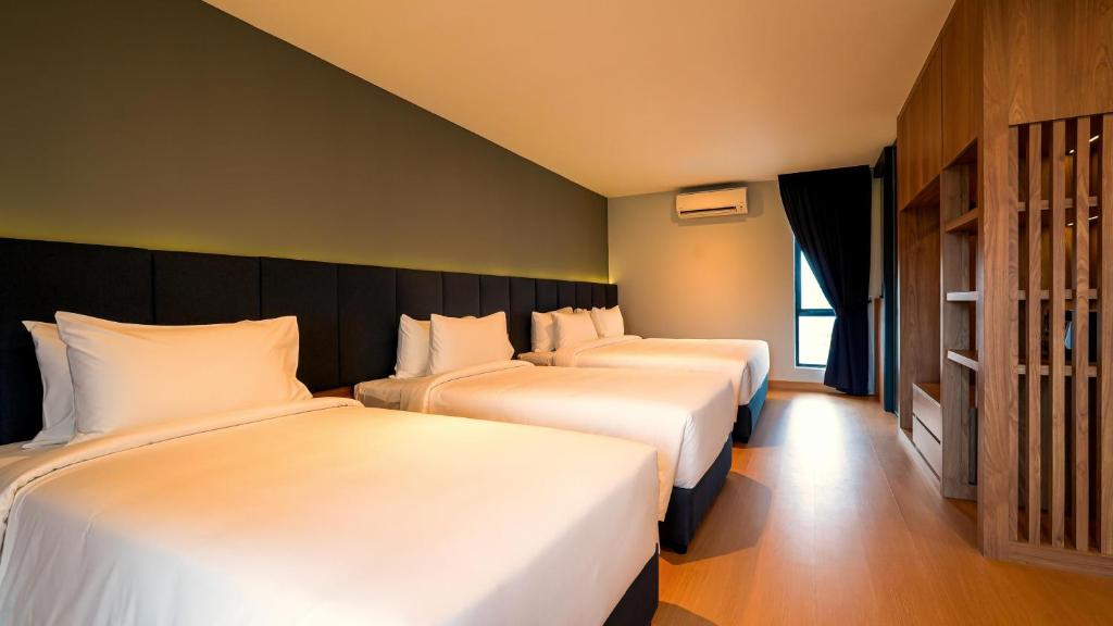 ein Hotelzimmer mit drei Betten mit weißer Bettwäsche in der Unterkunft Bond Hotel Rawang in Rawang