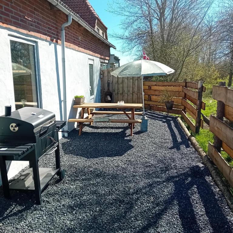 a picnic table with an umbrella and a grill at Heidis Loft in Vidstrup