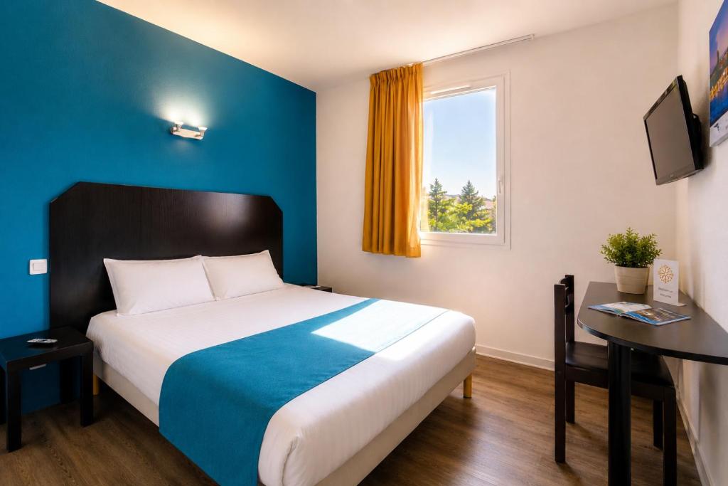 a bedroom with a bed and a desk and a window at Audotel in Carcassonne