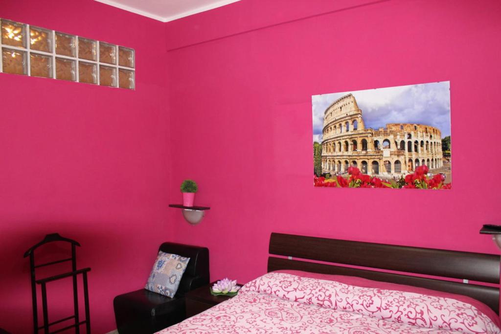 Un dormitorio con una pared rosa y una cama en Aracoeli, en Roma