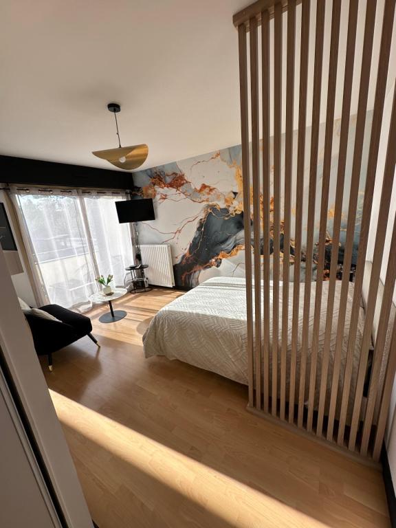 a bedroom with a bed and a large painting on the wall at Charmant Studio in Vitré