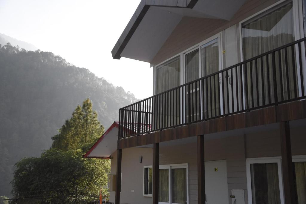 a building with a balcony with a mountain in the background at Hotel Dev Darshan in Uttarkāshi