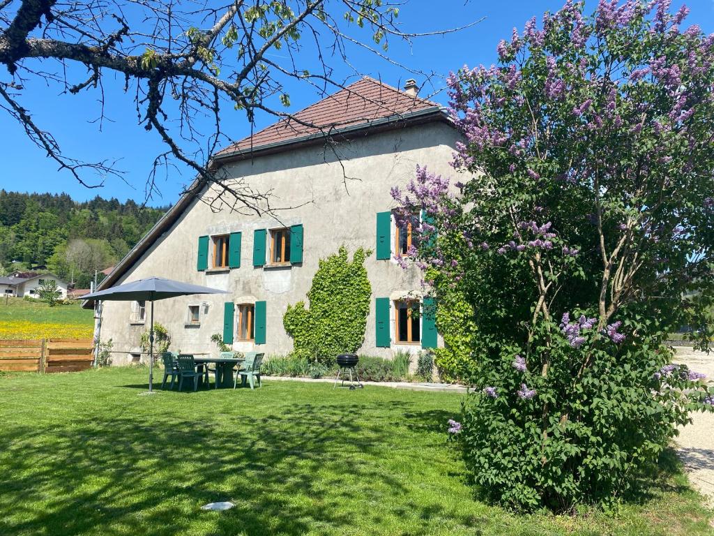 a large white building with green shutters at La ferme d'Auguste in Thorens-Glières