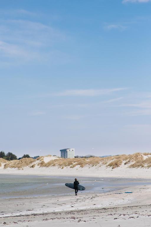 a person walking on the beach with a surfboard at Clarion Hotel Air in Sola