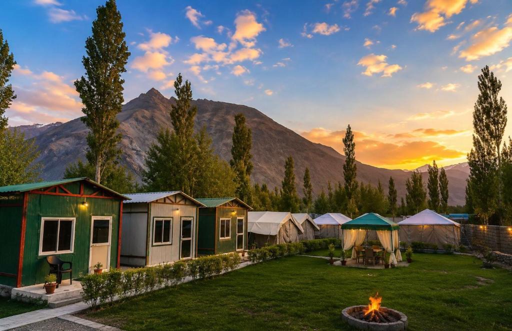 a group of tents in a field with a fire in the yard at Snowpeak Retreat in Hundar