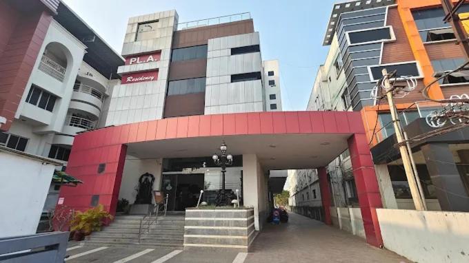 a building with a red and white facade and stairs at PLA RESIDENCY Trichy near Rockfort Temple in Tiruchirappalli