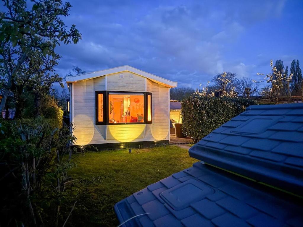 a small house with a large window on a yard at Tinyhouse mit Feuerstelle Capfun de Bongerd in Tuitjenhorn