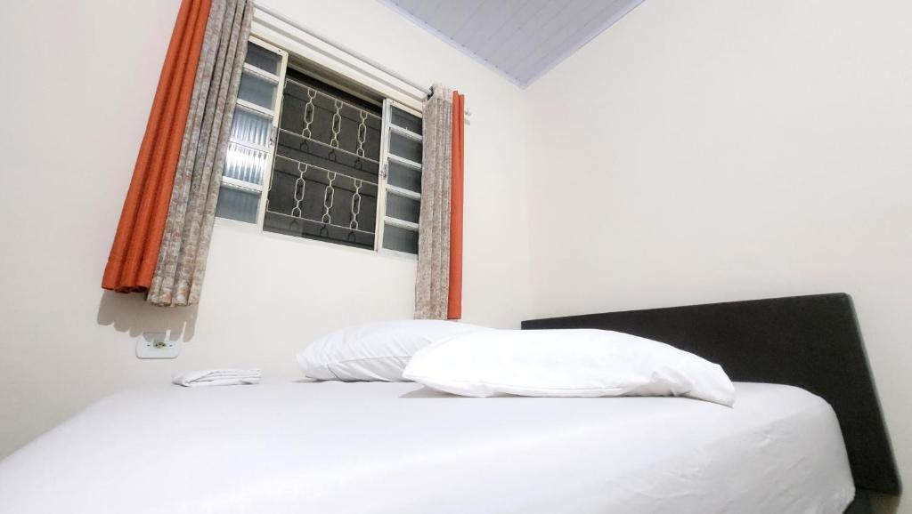 a white bed with two pillows and a window at Casa Benta in Aparecida