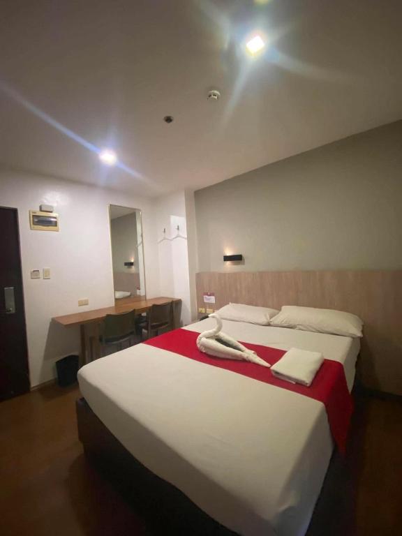 a bedroom with a large white bed with a red blanket at JLux Hotel in Manila