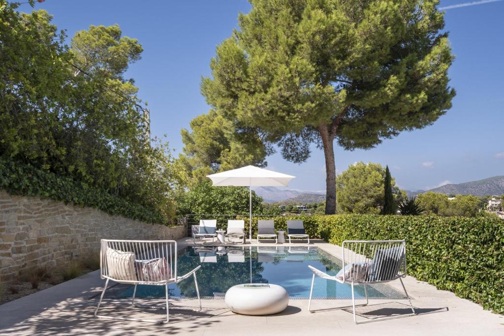 a pool with two chairs and an umbrella at BelleVue Cala Vinyes in Cala Vinyes
