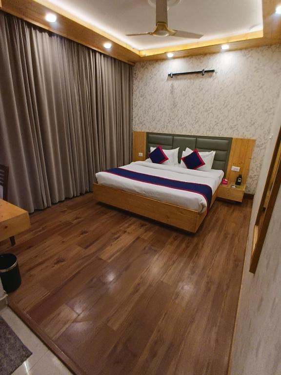 a bedroom with a large bed with a wooden floor at Hotel Bella Heights in Dharamshala
