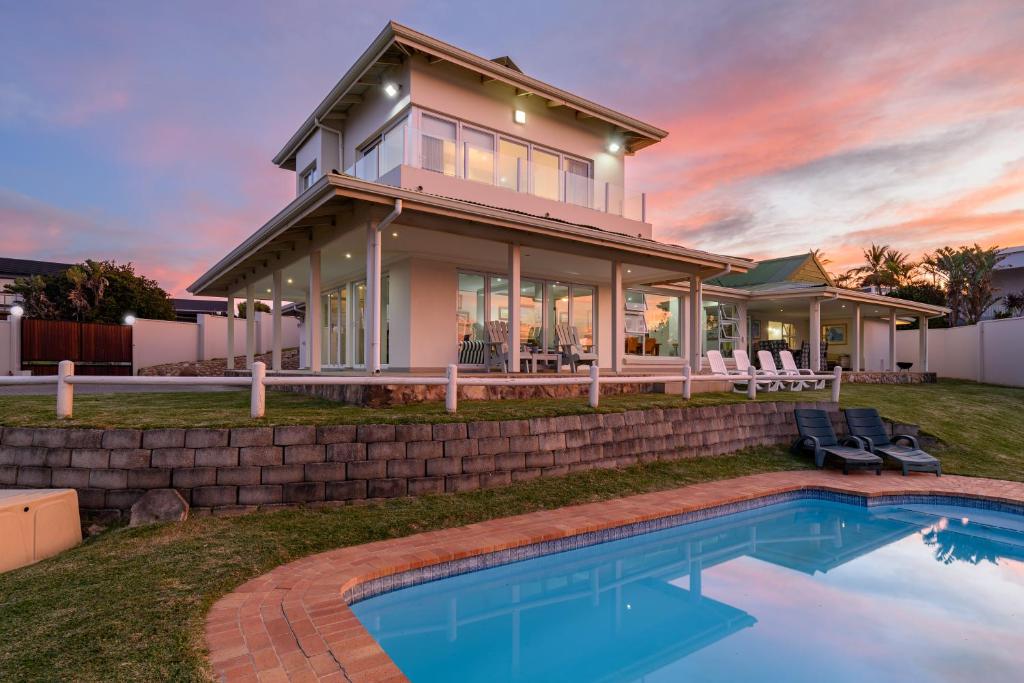 a house with a swimming pool in front of a house at Shabby View Beach House in Southbroom